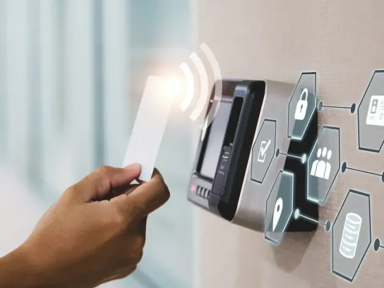 Hand presenting an access card to a wall-mounted reader