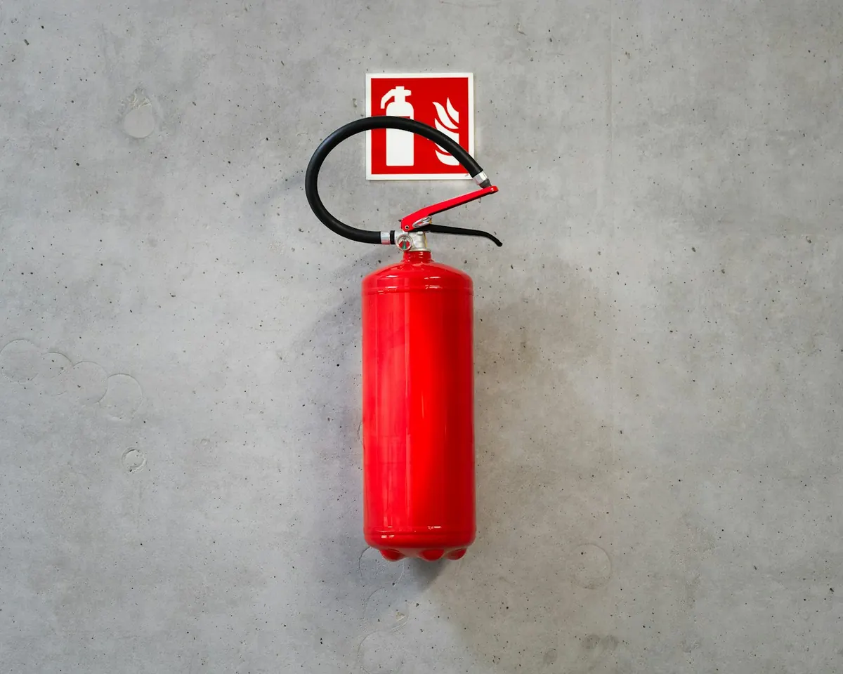 Fire extinguisher mounted on a concrete wall with its safety sign